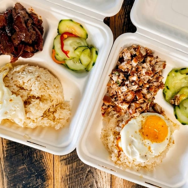 Two takeout containers with rice, meat, fried eggs, and pickled cucumbers on a wooden table.